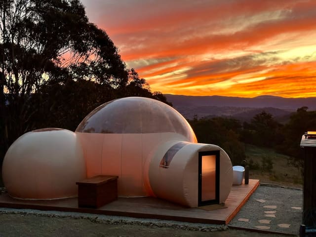 Bubble dome at dusk under a vivid orange sunset sky in the Megalong Valley.